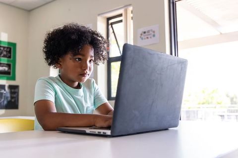 African American student focusing on laptop, studying digital learning and classroom tech