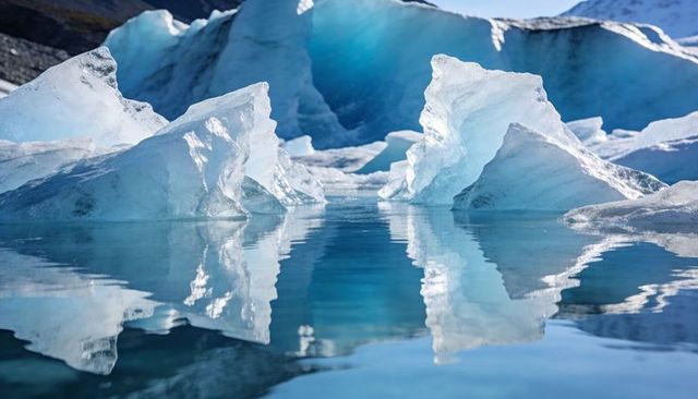 Glacier icebergs reflecting in calm meltwater lagoon, crystalline blue ice mirror