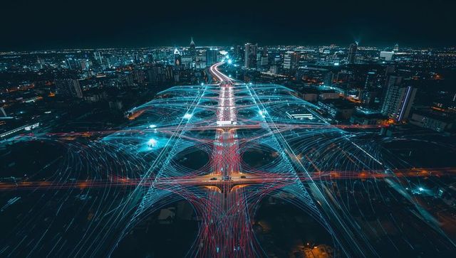 Multilane Interchange Curving through Neon Light Trails over City Night Skyline