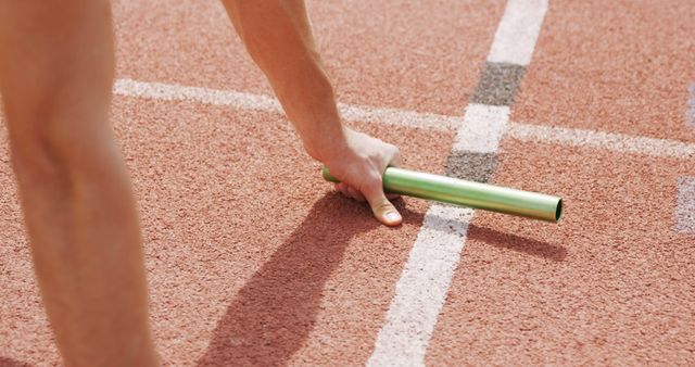 A close-up view of a relay baton being passed during a track event, with copy space. Such moments capture the crucial exchange in relay races that can determine the outcome of the competition.