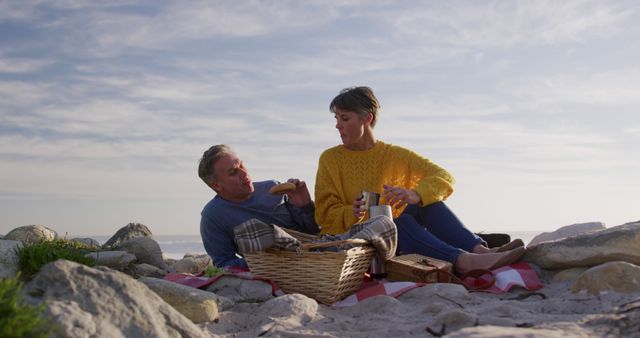 Mature couple enjoying picnic on rocky beach - Download Free Stock Images Pikwizard.com