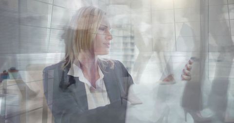 Executive holding tablet and glancing through glass reflections in modern office, double exposure