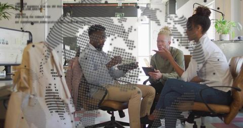 Team collaborating over tablets in modern open office with dotted glass partition