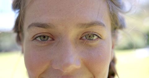 Cheerful Woman Smiling Outdoors with Green Eyes in Sunlight