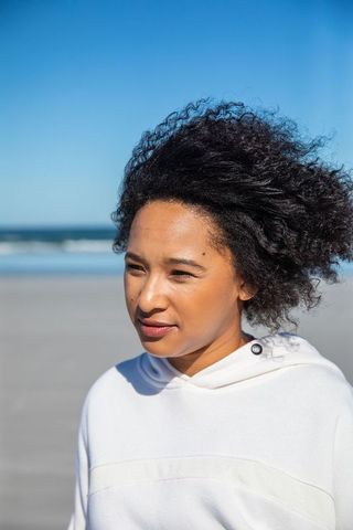 African American Woman Enjoying Ocean Breeze on Sunny Beach Day