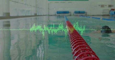 Competitive swimmer monitoring performance with digital data overlay over indoor pool lane