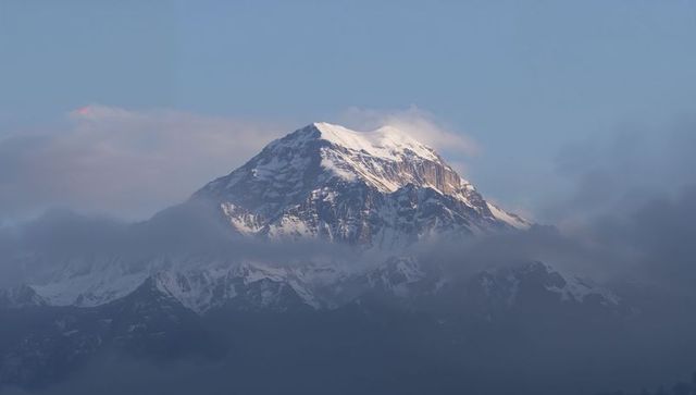 Sunlit Snow-Capped Alpine Summit Emerging Above Low Cloud Bank at Dawn