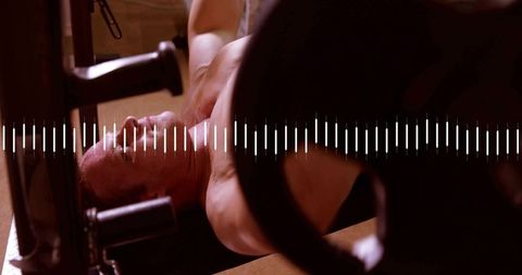 Muscular man lifting heavy barbell on bench press showing focus, power and intensity