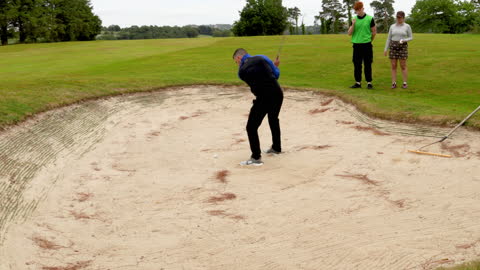 Golfer Playing from Sand Trap with Friends Watching on Course