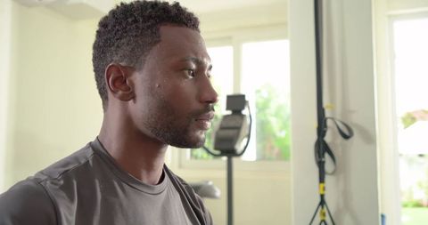 Mid-adult african american man pausing mid-workout in sunlit minimalist home gym