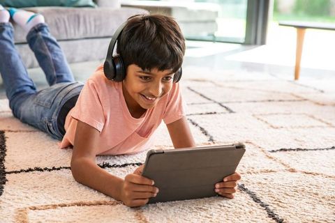Smiling boy wearing headphones using tablet indoors