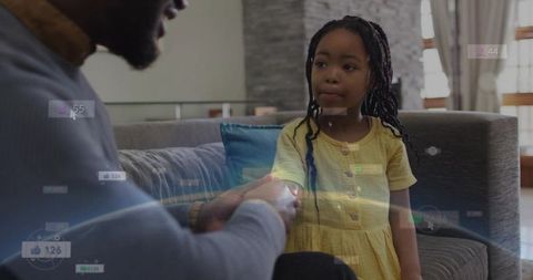 Parent holding child's hand on couch with social media badge overlays and warm sunlight