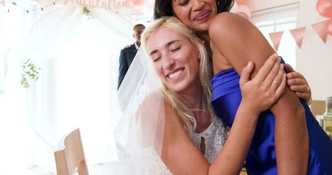 Smiling bride hugging friend in joyful wedding celebration
