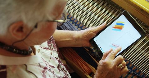 Senior woman creating digital art on tablet in craft workshop