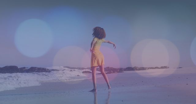 Woman is dancing on a beach during sunset with a bokeh light effect overlay. Ideal for concepts of freedom, joy, relaxation, and summer fun. Can be used in travel, lifestyle, vacation, and wellness promotions.