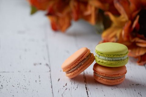 Pastel macarons stacking on white rustic wood with autumn flowers for bakery branding