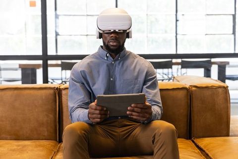 Man wearing vr headset holding tablet in modern office lounge