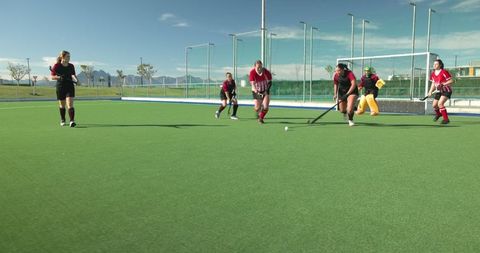 Female athletes in competitive field hockey match at sports complex
