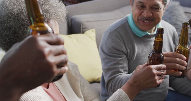 Elderly friends enjoying beers together at home, smiling and socializing in a relaxed atmosphere. Showing leisure and togetherness, this image is great for promoting social activities, seniors living, and community bonding.