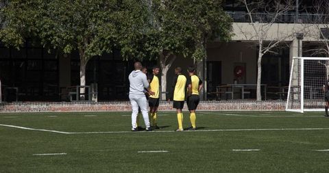 Soccer Players and Coach Strategizing on Outdoor Field