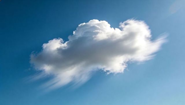 Drifting Cumulus Cloud with Wind-Sheared Wispy Edges Over Clear Blue Midday Sky