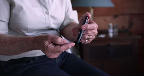 Senior Woman Checking Blood Sugar Level with Glucometer at Home