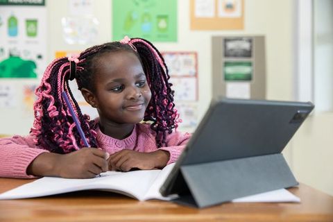 Young student engaged in virtual learning with tablet in classroom