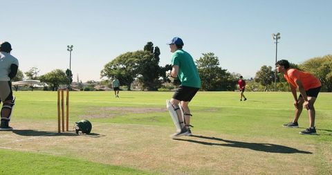 Youth cricket match african american batsman tapping bat while wicketkeeper returns ball