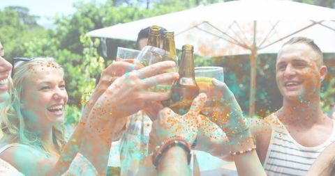 Friends Toasting Beer Bottles and Glasses on Sunny Backyard Patio with Colorful Confetti