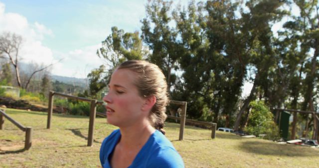 A young Caucasian woman appears to be jogging or exercising outdoors, with a blurred background indicating movement. Her focused expression and active posture suggest she is engaged in a fitness routine, emphasizing the importance of health and physical activity.