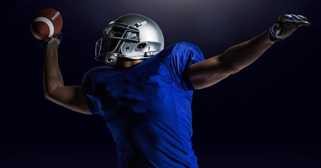American football player catching ball against black background