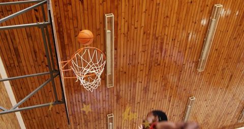 Basketball swishing through hoop in school gym capturing dramatic low-angle action