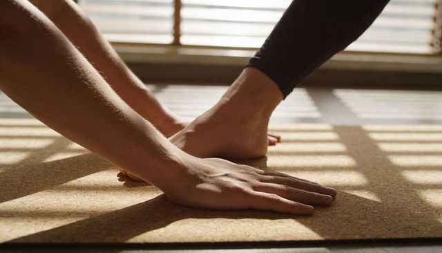 Sunlit cork mat yoga stretching with forearm pressing and foot balancing in calm light