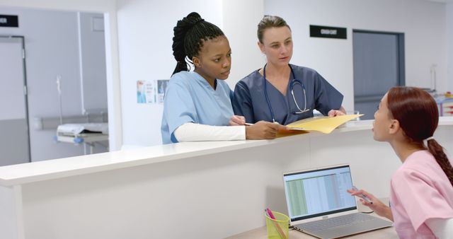 Medical Team Discussing Patient File at Hospital Reception - Download Free Stock Images Pikwizard.com