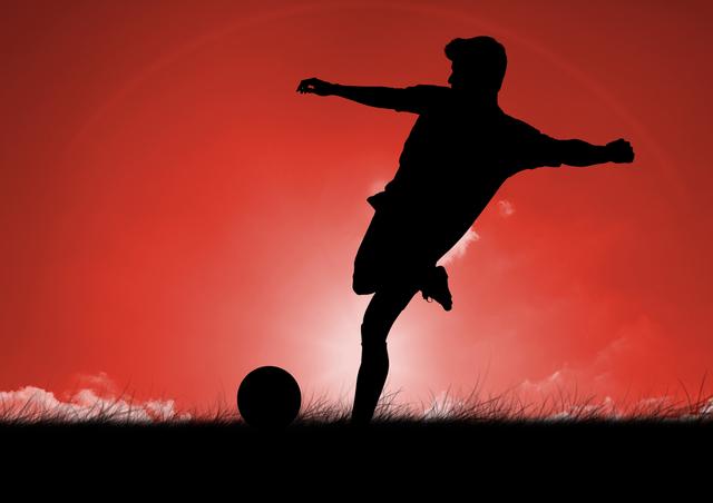 Silhouetted male football player kicking a ball against a vibrant red sky during dusk. Athlete is positioned on grass with dynamic action pose, creating a dramatic and visually appealing scene. Ideal for use in sports-related advertisements, motivational posters, or as a striking background for football and soccer news articles.