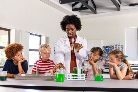 African american teacher conducting colorful science experiment with curious schoolchildren