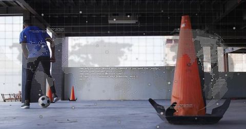 Urban indoor soccer dribbling around cones in industrial garage with world map overlay