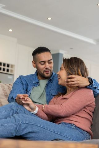 Couple cuddling on sofa in modern living room showing smartwatch and holding hands