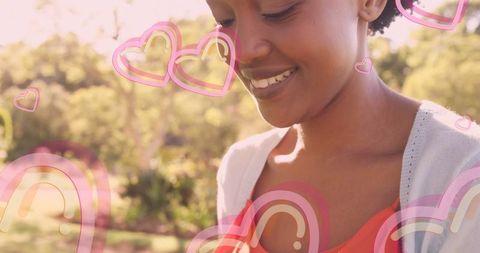 Cheerful Young Woman Smiling with Cartoon Hearts in Sunlit Park