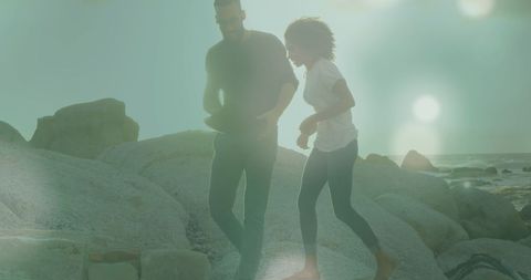 Couple Walking on Rocky Beach with Sunlight - Download Free Stock Images Pikwizard.com