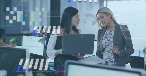 Asian professional and colleague collaborating over laptop with data overlays in office