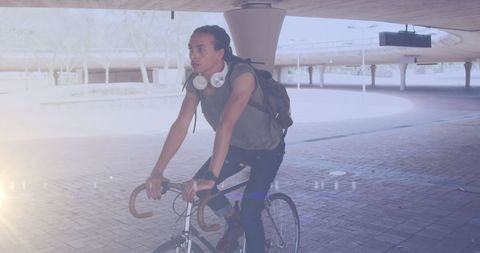 Biracial Man Cycling Under Urban Overpass on Sunny Day