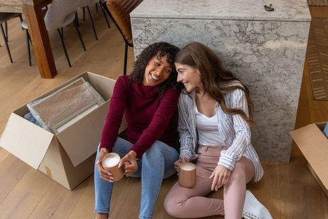Happy Friends Sipping Coffee During Moving Day in Cozy Kitchen