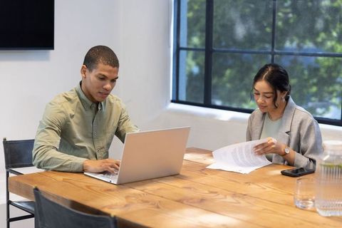 Diverse Team Collaborating with Laptop and Documents in Modern Office