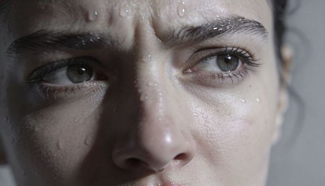 Close-up wet face with intense gaze and textured skin droplets macro beauty portrait raw