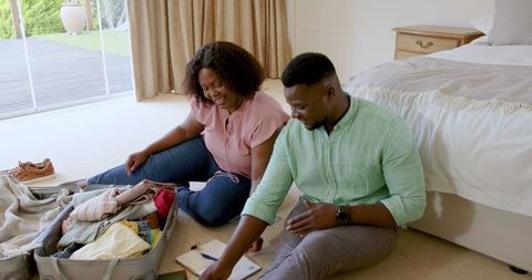 Happy Couple Packing Suitcase in Bedroom