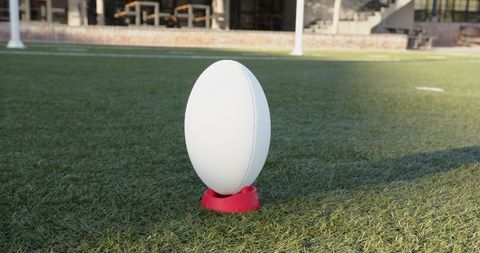 White rugby ball on red kicking tee sports scene