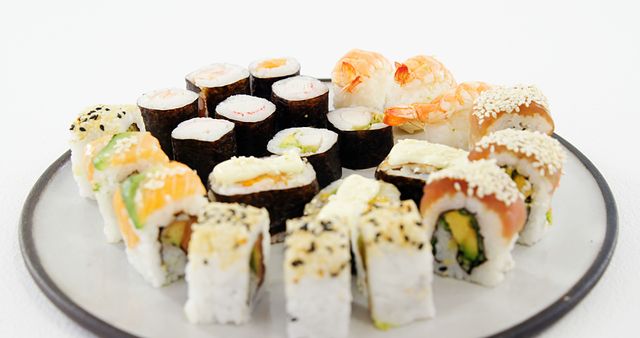 An assortment of sushi rolls is presented on a plate, showcasing a variety of fillings and toppings. Sushi, a traditional Japanese dish, has gained international popularity for its flavors and artistic presentation.