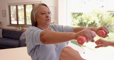 Senior Woman Exercising with Dumbbells Guided by Physiotherapist