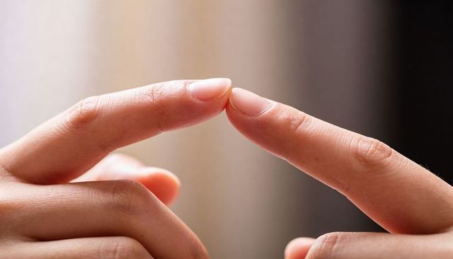 Closeup of two index fingers touching tips showing fingernails skin texture